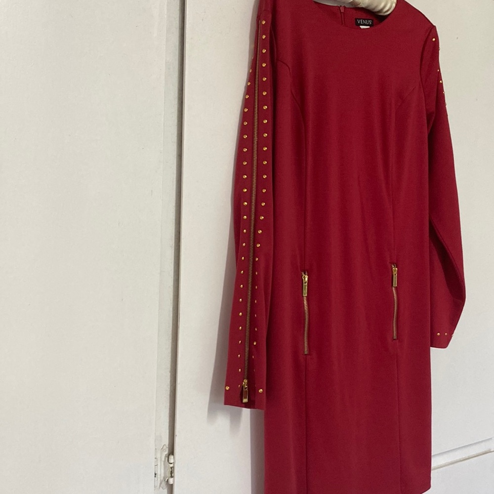 Red dress accessorized with gold studs and gold zippers.